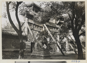 Marble lion in first courtyard and south facade of pai lou leading to second courtyard at Yong he gong