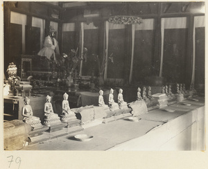 Altar with a Buddha statue wearing a mantle and Buddha figurines at Tan zhe si