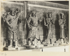 Statues of two celestial kings one with a stringed instrument and one holding an animal (left), a four-armed Bodhisattva, and an official (right) at Xi yu si