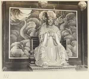 Shrine interior at Hei long tan showing a shrine figure in front of a mural with dragon and clouds