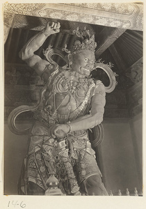 Temple interior at Bi yun si showing a statue of a guardian figure with sceptre