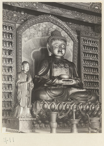 Temple interior showing statues of Buddha and attendant, ritual objects, and walls with Bodhisattva reliefs at Wan shou si