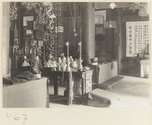 Temple interior showing altar with ritual objects, offerings of food, musical instruments, altar cloths, and hanging scrolls at Fa yuan si
