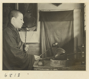 Buddhist nun holding a hand chime and striking a mu yu