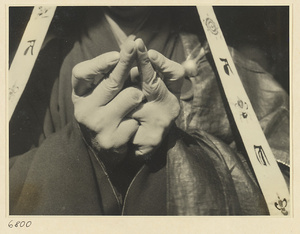 Nun with hands forming Buddhist mudra and wearing headdress with Sanskrit inscriptions