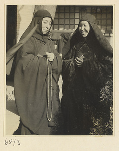 Buddhist nuns with rosary in courtyard of nunnery