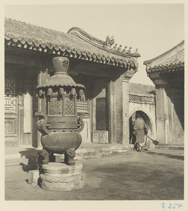Courtyard with an incense burner and a man exiting through a moon gate at Bai yun guan