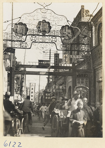 Western end of Dashalan Street showing gate, shop signs, rickshaw puller, and pedestrians