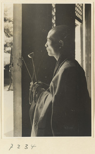 Monk striking a handchime at Jie tai si