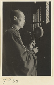 Monk striking a gong at Jie tai si