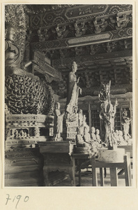 Interior of a temple building at Jie tai si showing altar with a giant Buddha on a lotus throne and other statues