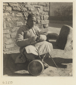 Blind fortune teller with staff and drum called a dian gu