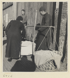 Rice candy vendor with baskets of rice candy suspended from shoulder pole