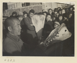 Street entertainer attracting a crowd with cowbone clappers and bells