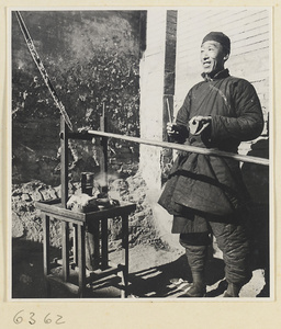 Rice cake vendor holding a wooden tap box called a bang zi next to portable stove