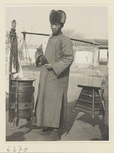 Street barber carrying equipment and stool on should pole and attracting customers with an iron huang or suo zi