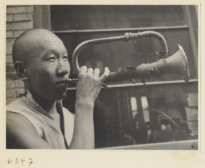 Itinerant knife sharpener blowing a brass instrument called a xiao tong jue or tiao zi to attract customers