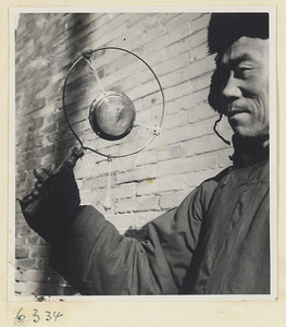 Vendor of sewing supplies holding a gong called a yun luo or ling zi