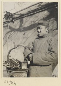 Street vendor hawking cigarettes and candied fruit called tang hu lu from a basket