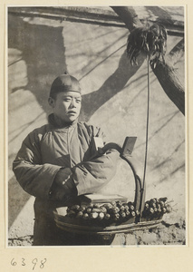 Street vendor hawking cigarettes and candied fruit called tang hu lu from a basket