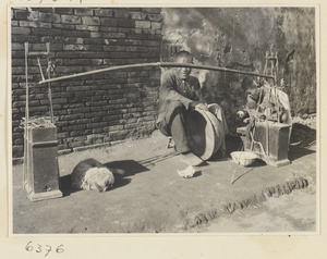 Itinerant ceramic repairman at work next to toolbox and gong called a tang or xiao lu jiang