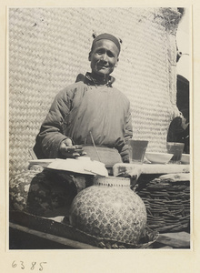 Vendor at a food stand selling drinks holding metal hand clappers called bing zhan