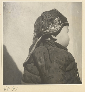 Child wearing a fringed hat with embroidery