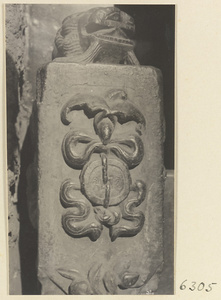 Carved door stone with bat, knot, and coin motifs