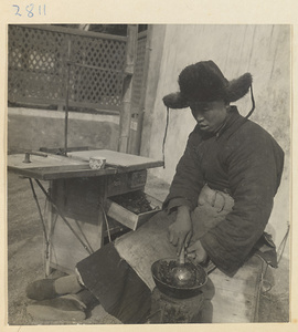 Tracery candy vendor heating candy on a portable stove