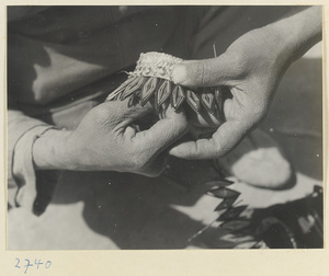 Woman making a souvenir out of braided colored straw at Bei'anhe