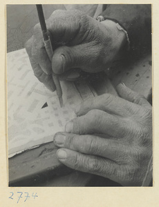 Paper-cut maker beginning to cut through soot pattern with a knife