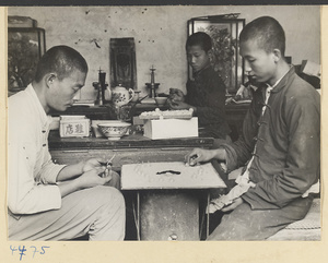 Men preparing glass balls for assembly as artificial grapes as boy watches next to altar in background