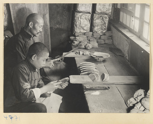 Man with a file and boy with a chisel finishing wooden combs in a workshop