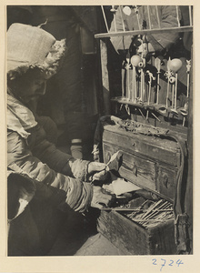 Candy vendor at his stand attaching molded candy to a bamboo stick