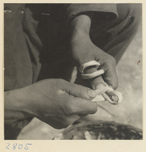 Woman forming a loop of twisted husks to make a maize straw cushion