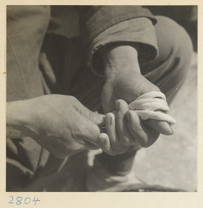 Woman wrapping twisted husks around her thumb to make a maize straw cushion