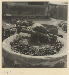 Courtyard of a paper-making shop showing grindstone with paper pulp and roller