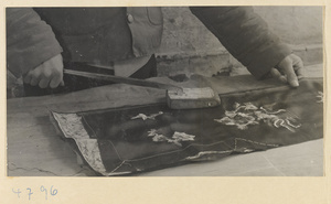 Man ironing a piece of emboidered silk cloth