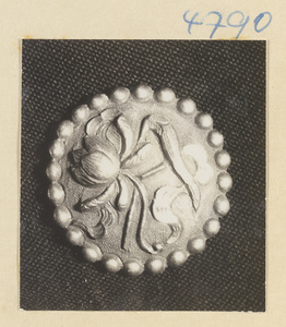 Silver button with relief work showing the attributes of He Xiangu, one of the eight Daoist immortals
