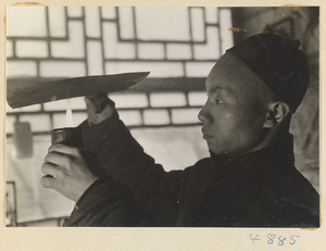 Man coating a sheet of metal with soot in a workshop that makes iron pictures