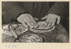 Man placing a paper stencil over a metal sheet in a workshop that makes iron pictures