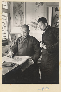 Man watching an artist making a scroll painting on silk