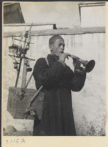 Street entertainer blowing a suo na to attract an audience for a performance of trained mice