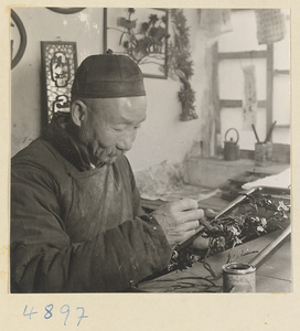 Man painting or coating an iron picture in a workshop that makes iron pictures