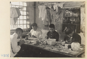 Four men at a workbench in cloisonné workshop