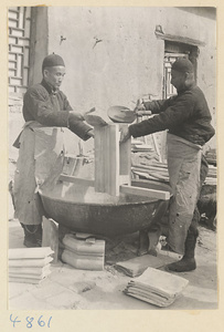 Men glazing roof tiles over a vat at a tile and brick factory near Mentougou Qu