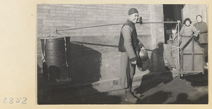 Puppeteer with gongs called luo (larger) and tang luo (smaller) carrying puppet theater and boxes of equipment on shoulder pole