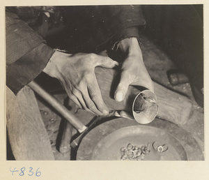 Coppersmith working on a pitcher in a workshop