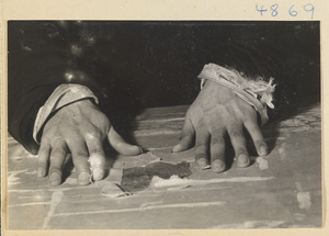 Man in a scroll-mounting shop repairing the silk backing of a painting