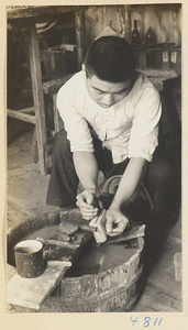 Man working on a cloisonné box over a bucket of water